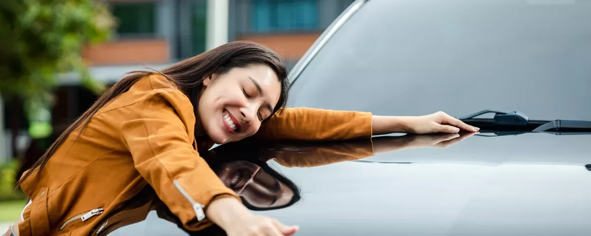Woman looking happy lying on car bonnet